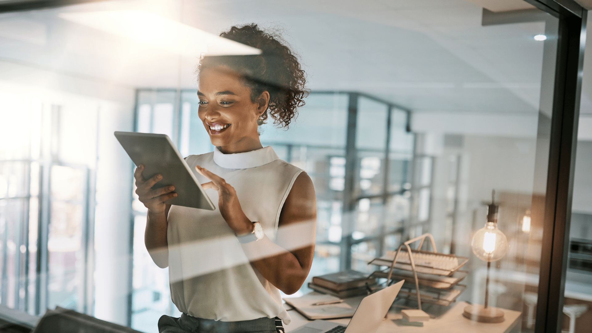 A woman working on a tablet, happy.